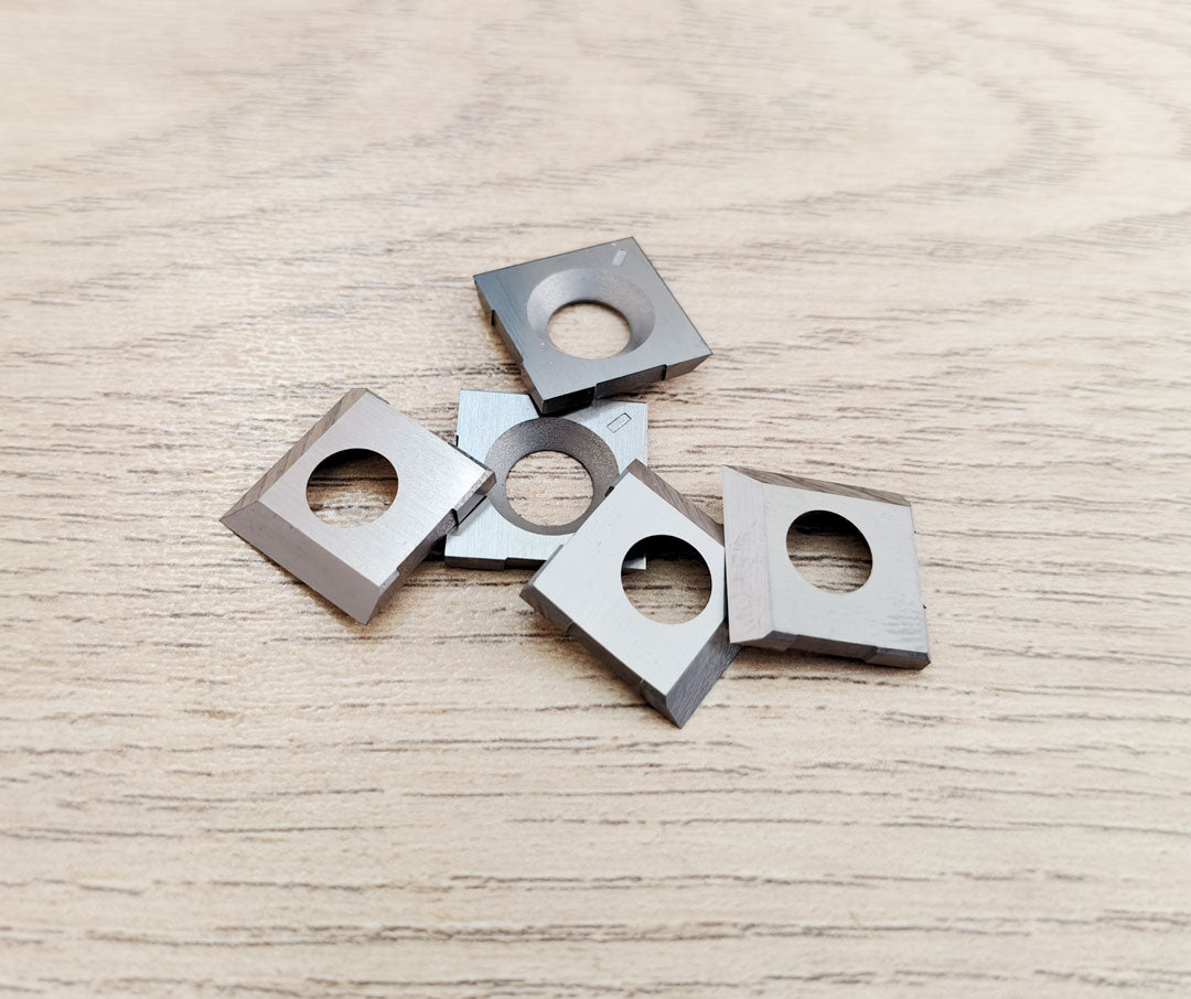 14.27x14.27x2.0mm-50° carbide cutter knives, square shape inserts, 5 pieces on wooden background.