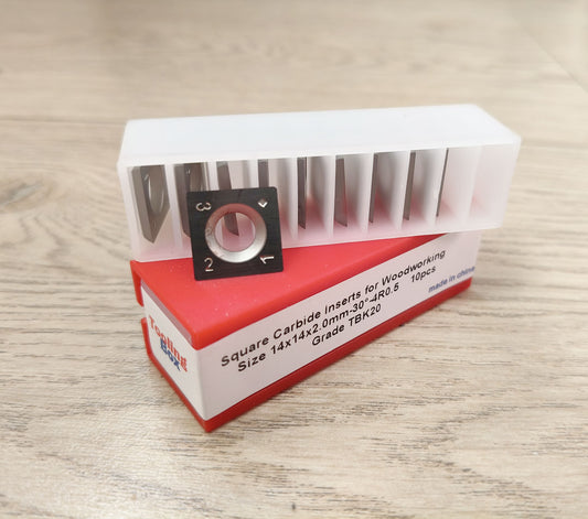 Square carbide inserts for woodworking on a red and white box with text on a wooden surface